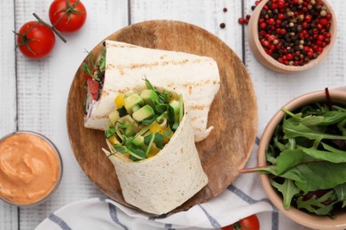 Photo of Delicious sandwich wraps with fresh vegetables, sauce, tomatoes and peppercorns on white wooden table, flat lay