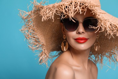 Photo of Attractive woman in fashionable sunglasses and wicker hat against light blue background. Space for text