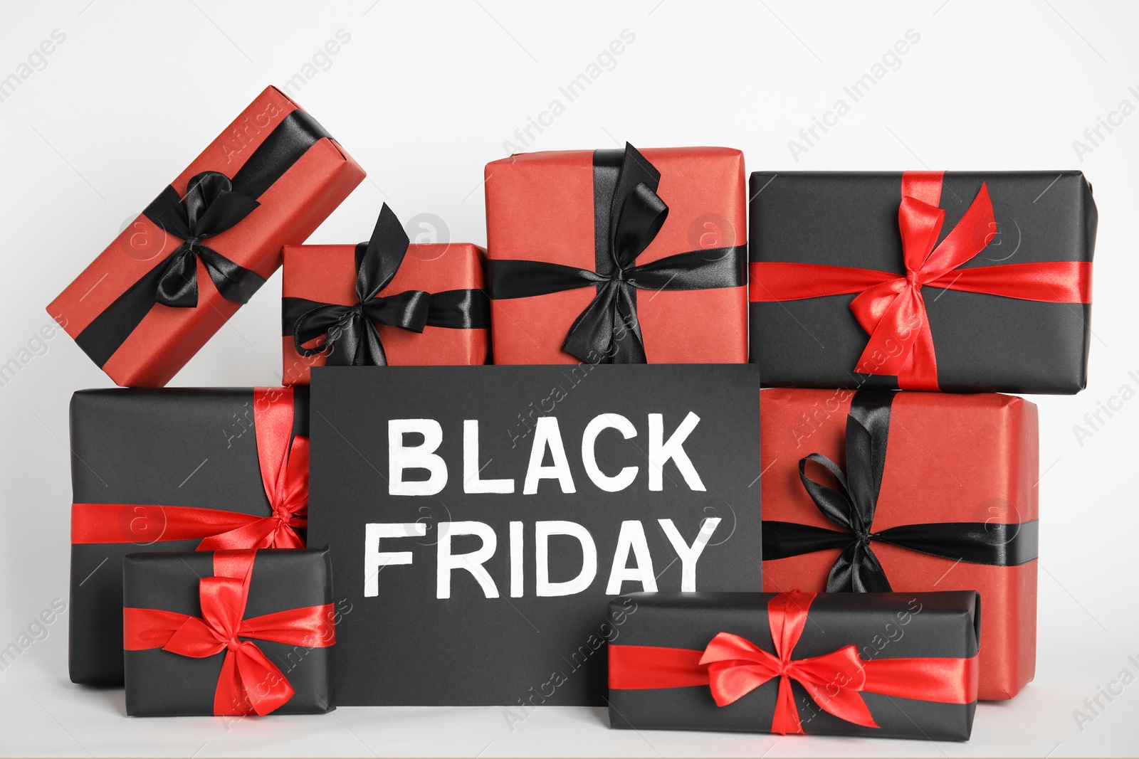 Photo of Many gift boxes and sheet of paper with words Black Friday on white background