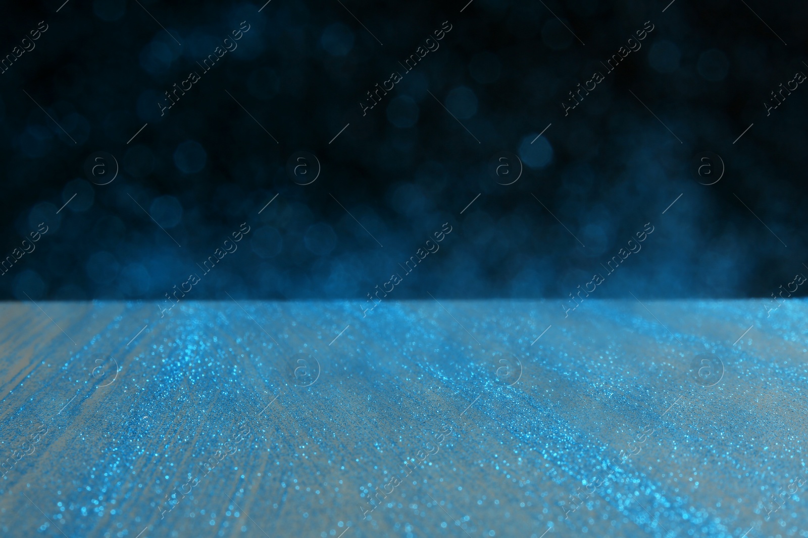 Photo of Glitter on table against dark background. Bokeh effect