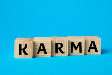 Photo of Word Karma made of cubes with letters on light blue background