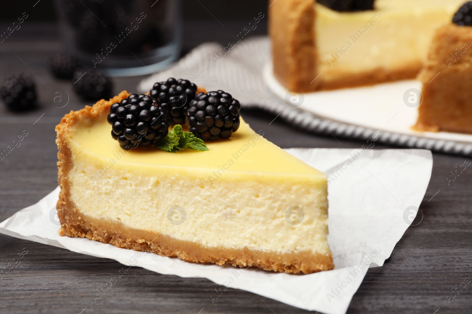 Photo of Piece of delicious cheesecake decorated with blackberries on table