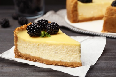 Photo of Piece of delicious cheesecake decorated with blackberries on table