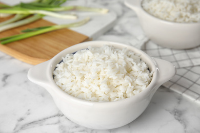 Photo of Bowl with tasty cooked rice on marble table, closeup