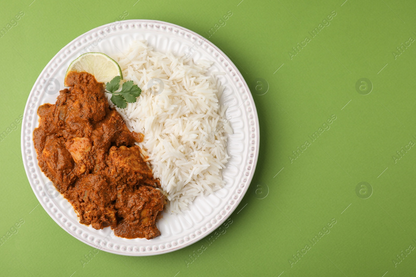 Photo of Delicious chicken curry with rice on green background, top view. Space for text