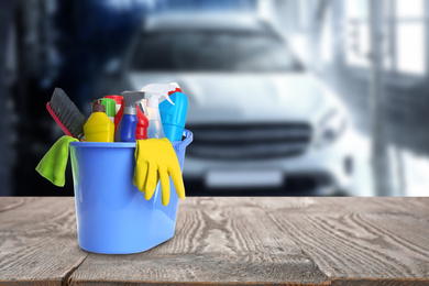 Image of Bucket with cleaning supplies on wooden surface at car wash. Space for text