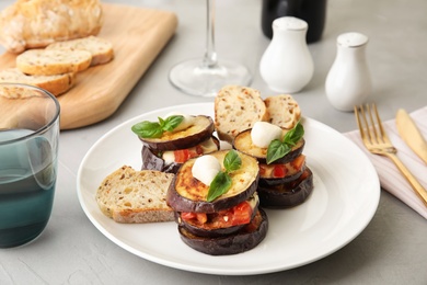 Baked eggplant with tomatoes, cheese and basil served on table