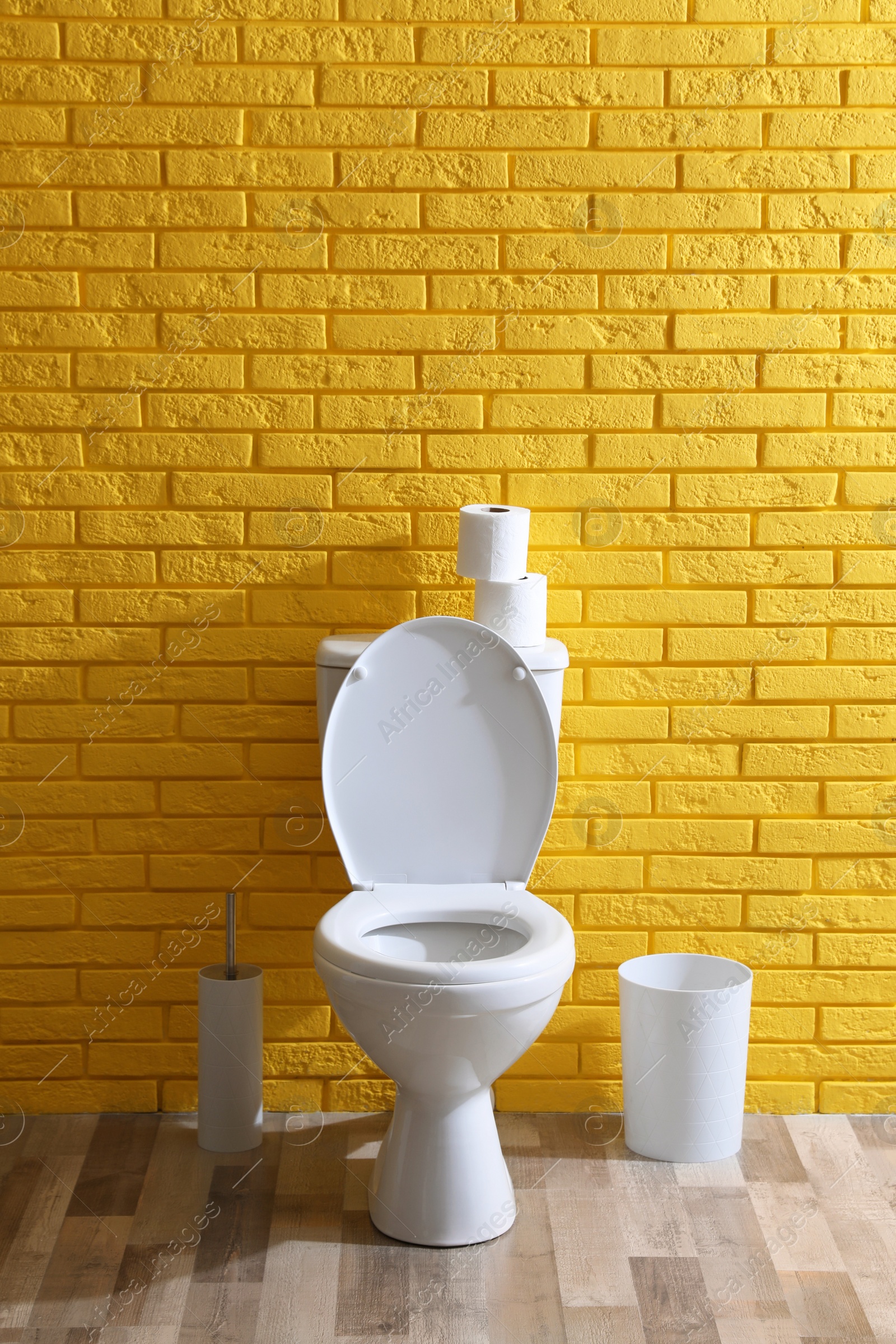 Photo of Simple bathroom interior with toilet bowl near yellow brick wall indoors. Home design