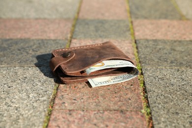 Photo of Brown leather purse on pavement outdoors, closeup. Lost and found