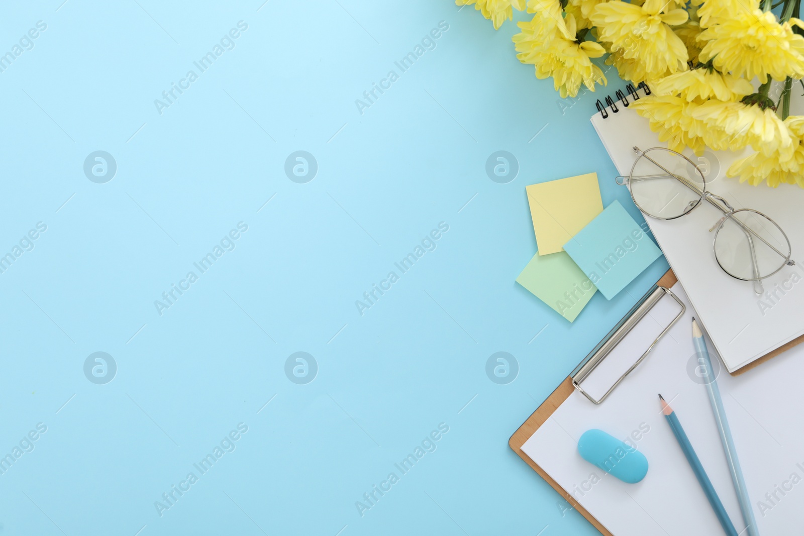 Photo of Beautiful flowers and stationery on light blue background, flat lay with space for text. Teacher's Day