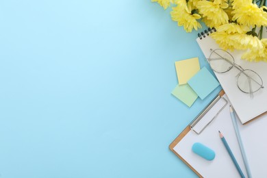 Beautiful flowers and stationery on light blue background, flat lay with space for text. Teacher's Day