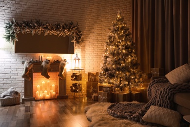 Photo of Stylish interior with beautiful Christmas tree and artificial fireplace at night