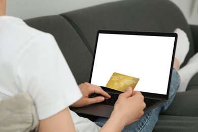 Photo of Woman with credit card using laptop for online shopping on sofa, closeup