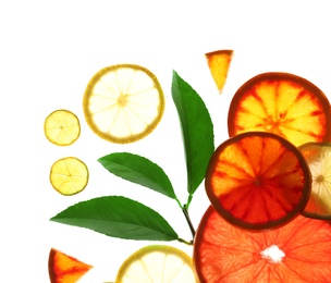 Illuminated slices of citrus fruits and leaves on white background, top view