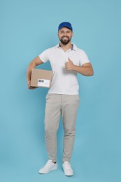 Photo of Courier holding cardboard box on light blue background
