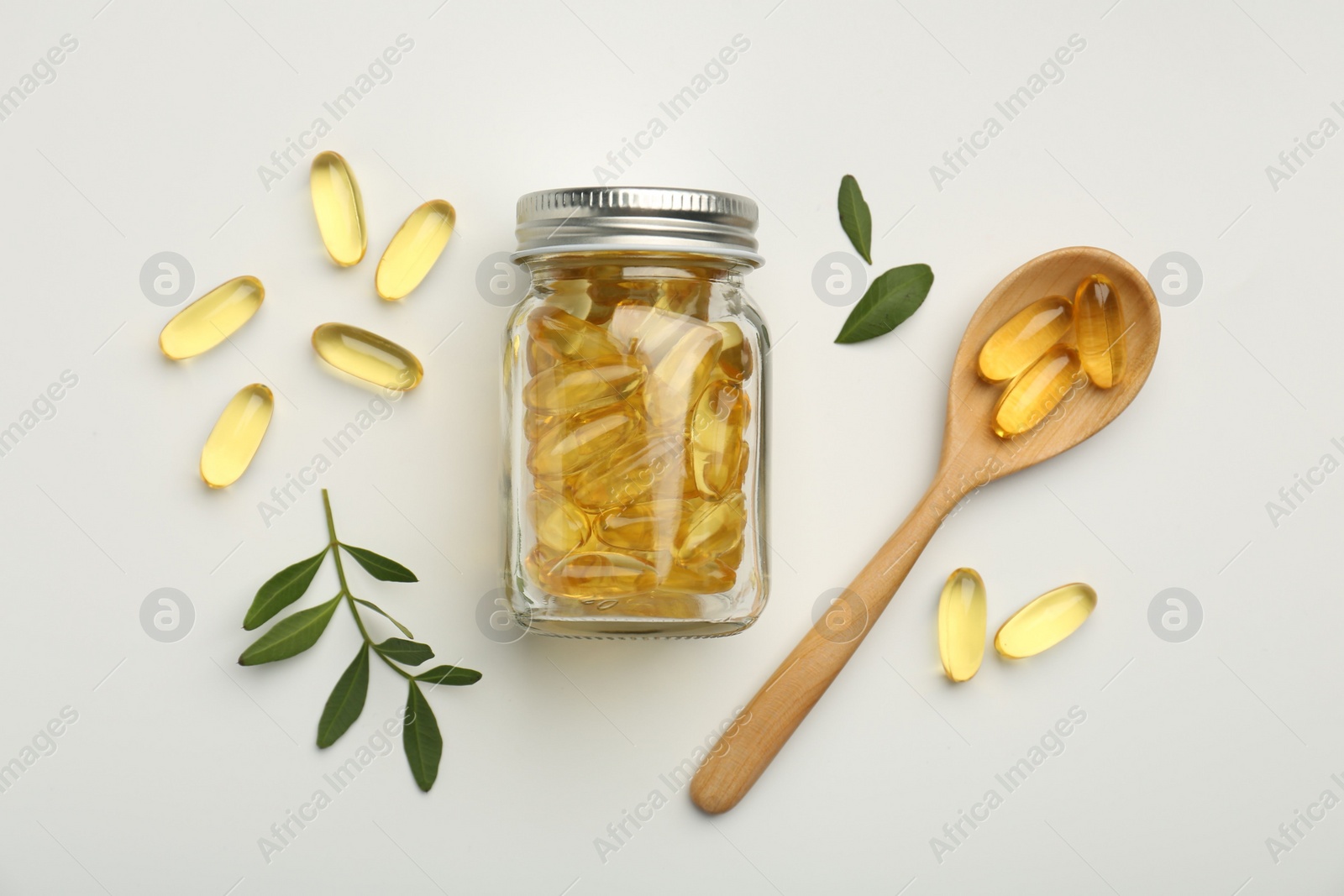 Photo of Bottle, vitamin capsules, spoon and leaves on white background, flat lay