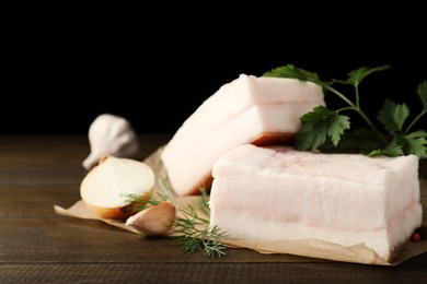 Photo of Tasty salt pork with herbs, onion and garlic on wooden table, closeup