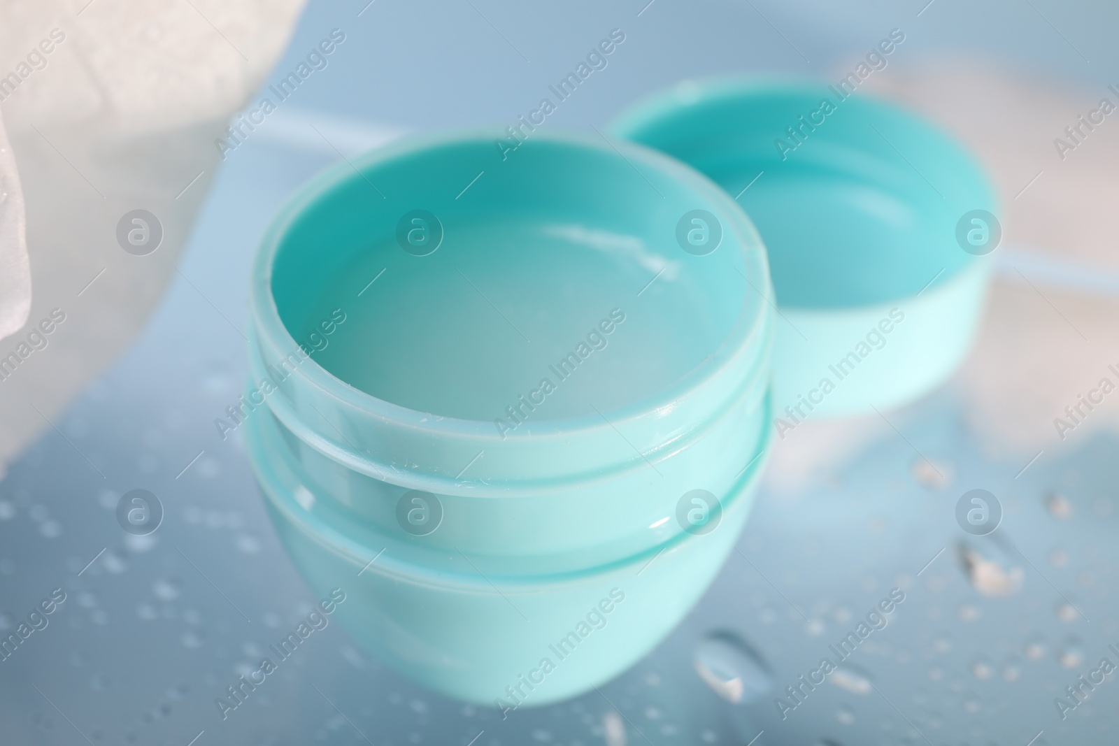 Photo of Lip balm and water drops on glass surface, closeup