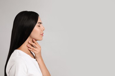 Photo of Young woman doing thyroid self examination on light background. Space for text
