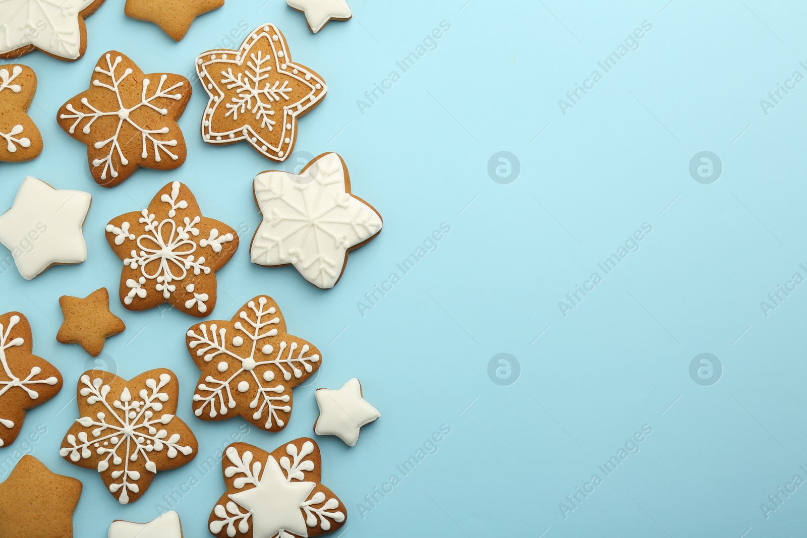 Photo of Tasty star shaped Christmas cookies with icing on light blue background, flat lay. Space for text