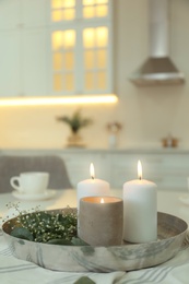 Photo of Beautiful eucalyptus branches, flowers and burning candles on napkin in kitchen, space for text. Interior element