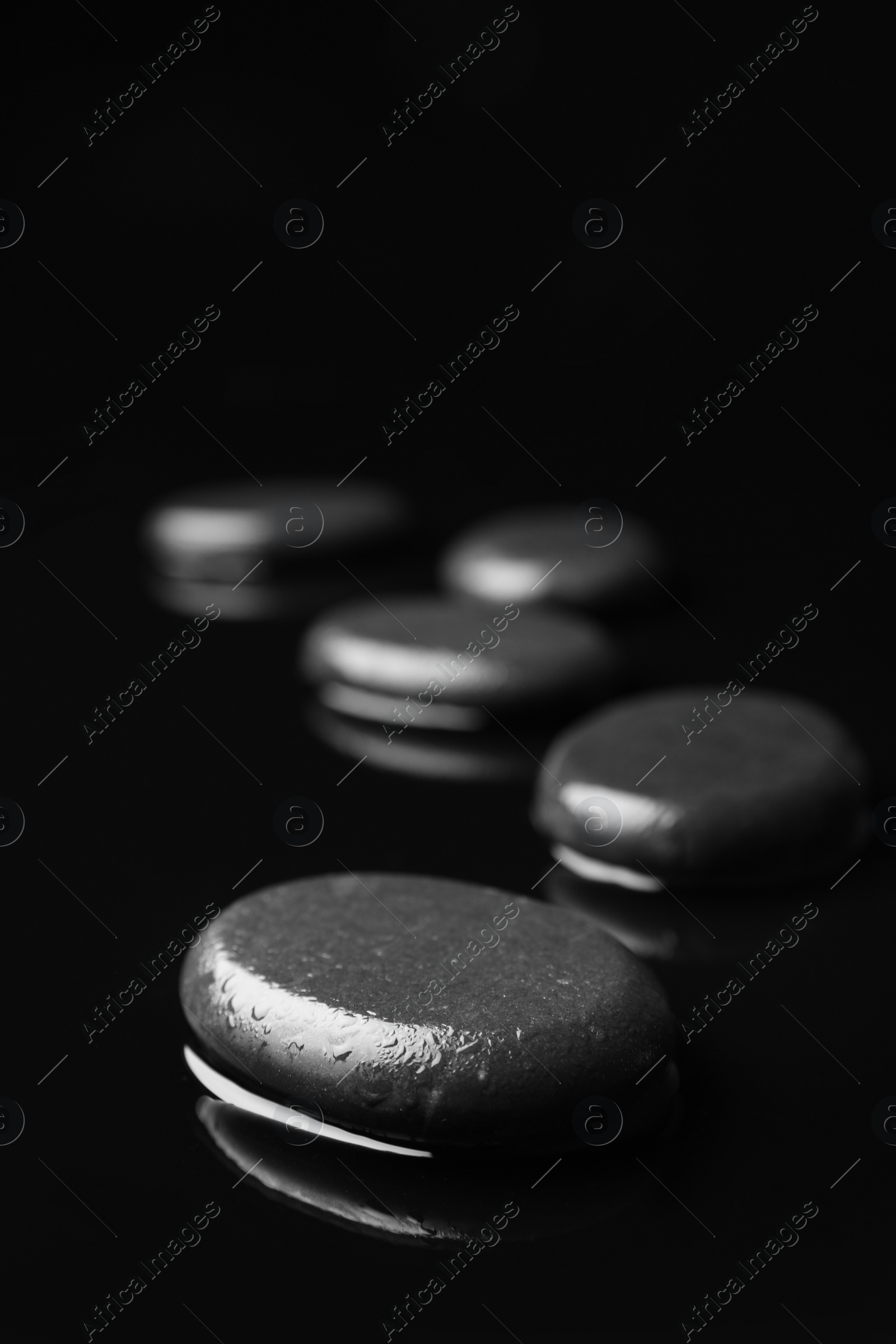 Photo of Wet spa stones on black background. Space for text