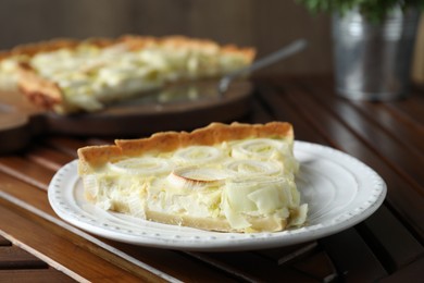 Photo of Plate with piece of tasty leek pie on wooden table, closeup