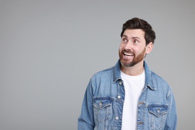 Photo of Portrait of happy surprised man on grey background, space for text