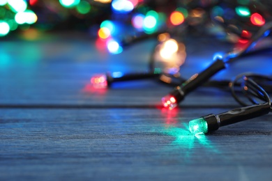 Glowing Christmas lights on wooden table, closeup