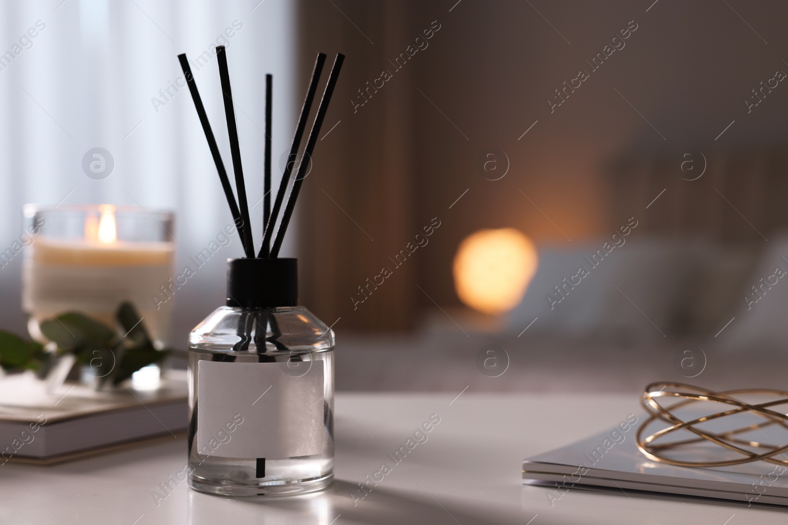 Photo of Reed diffuser on white table indoors. Space for text