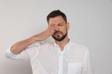 Man suffering from eyestrain on light background