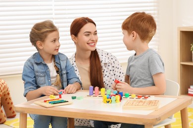 Photo of Happy mother and children playing with different math game kits at desk in room. Study mathematics with pleasure