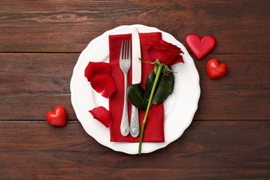 Photo of Romantic place setting with red rose and decorative hearts on wooden table, top view. St. Valentine's day dinner