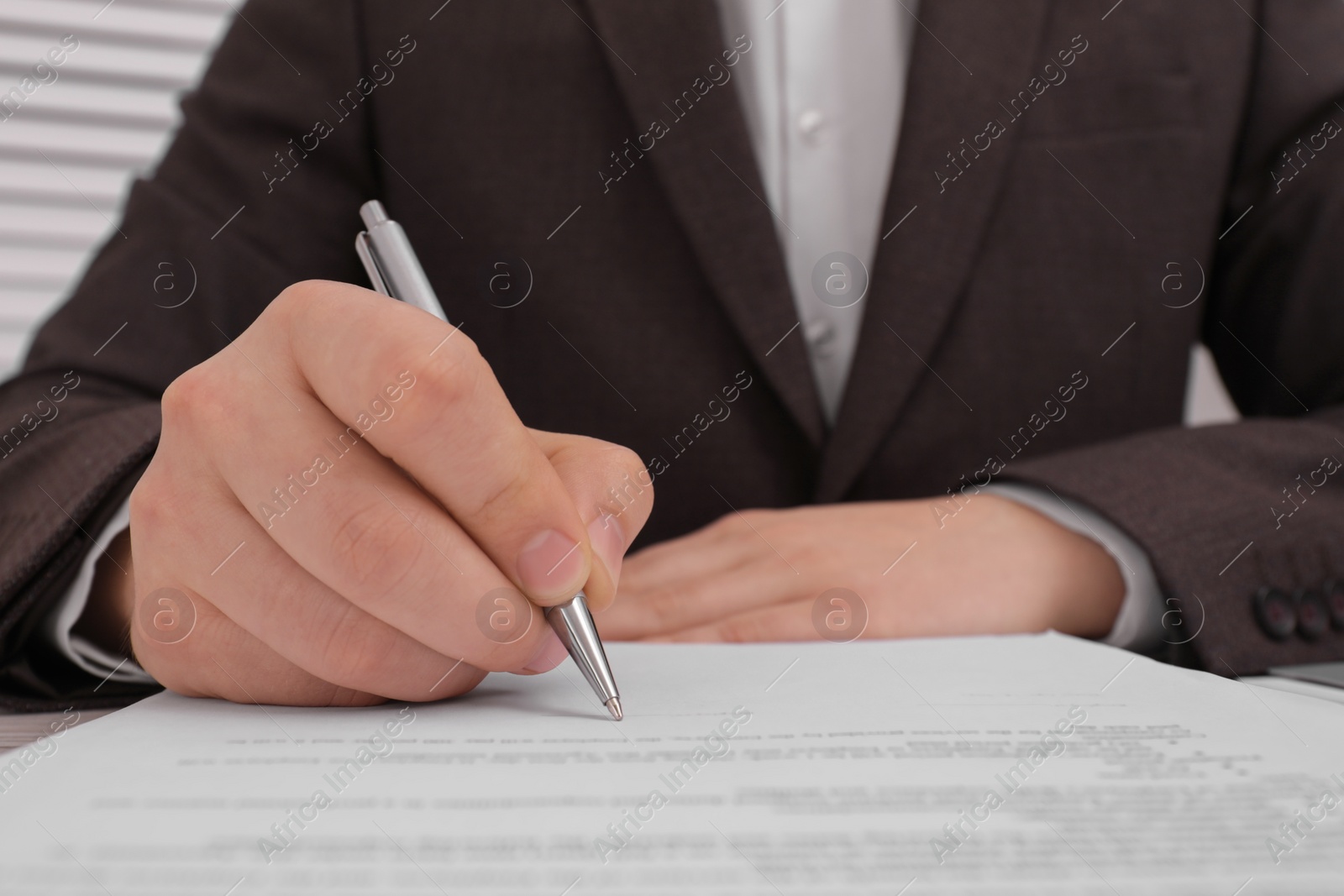 Photo of Man signing document at table, closeup view