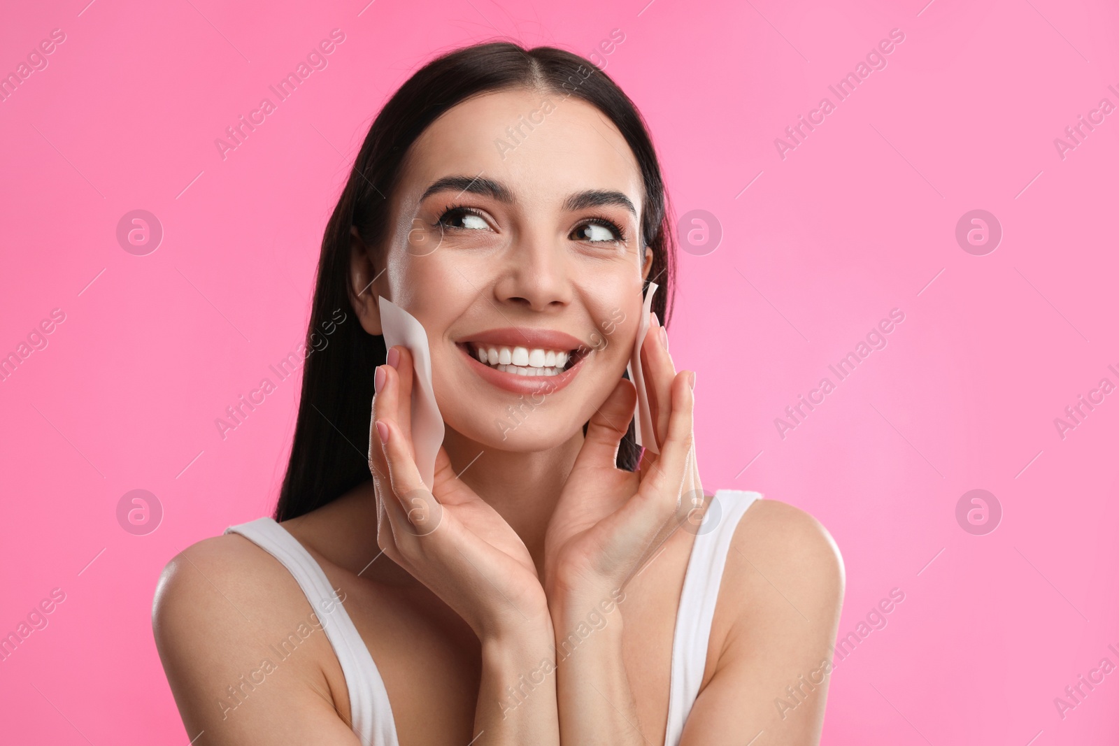 Photo of Beautiful woman using mattifying wipes on pink background, space for text