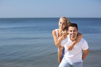 Happy young couple having fun at beach on sunny day