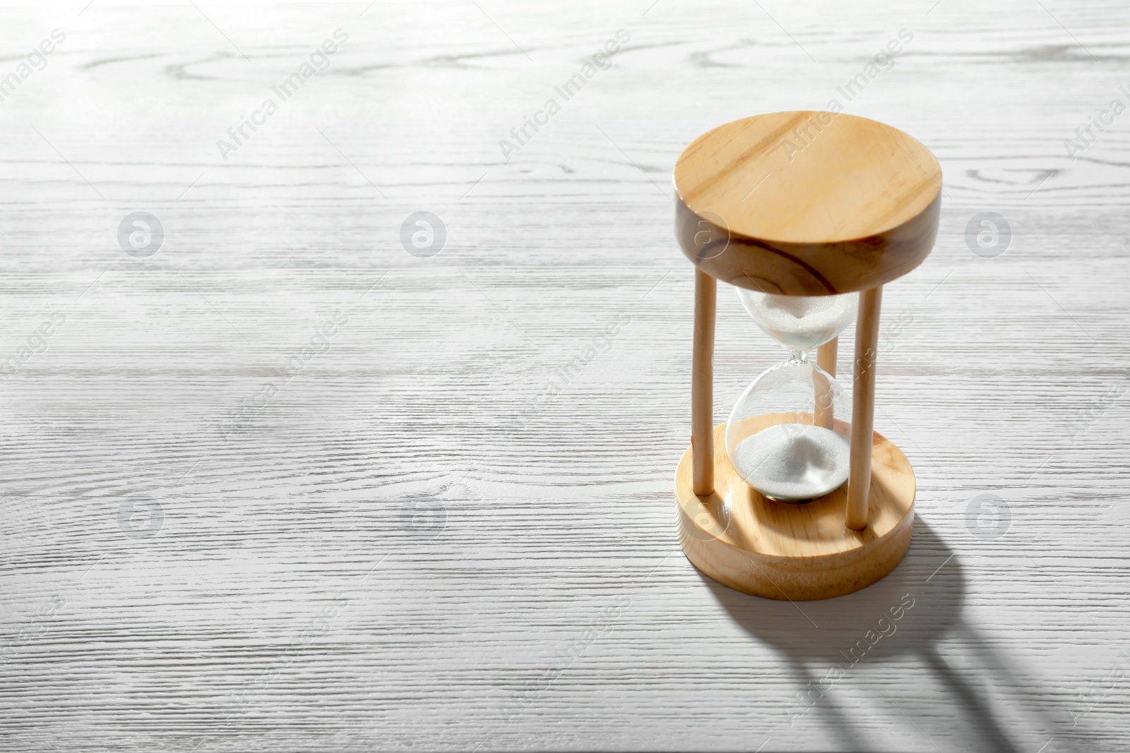 Photo of Hourglass with flowing sand on light wooden background. Time management