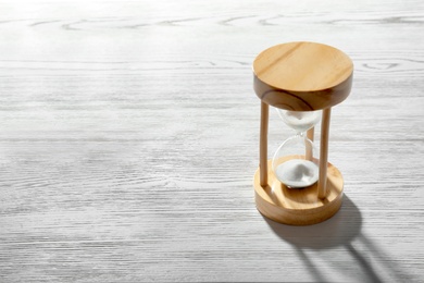 Hourglass with flowing sand on light wooden background. Time management