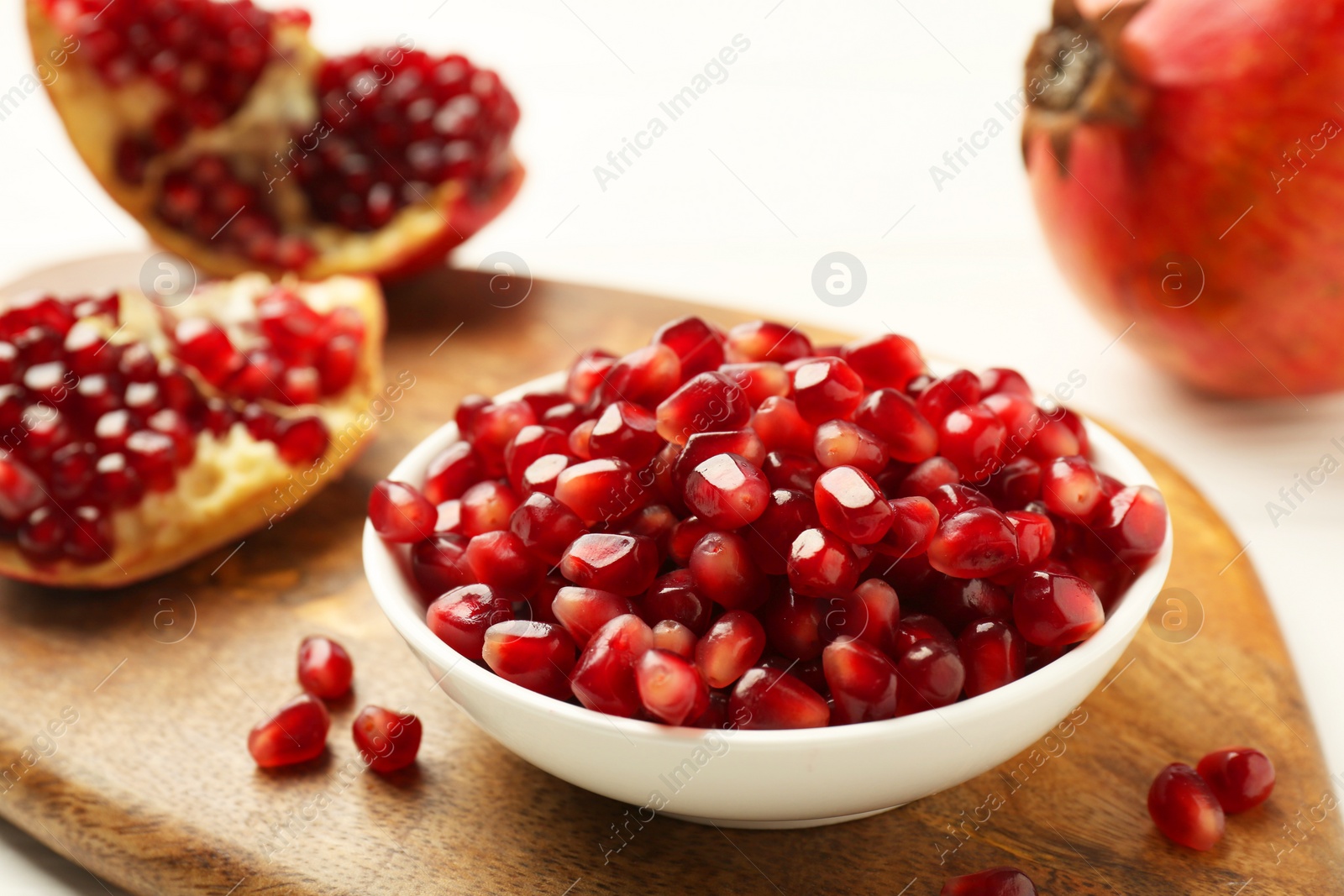 Photo of Ripe juicy pomegranate grains on white table, closeup