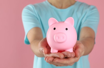 Photo of Woman with piggy bank on pink background, closeup