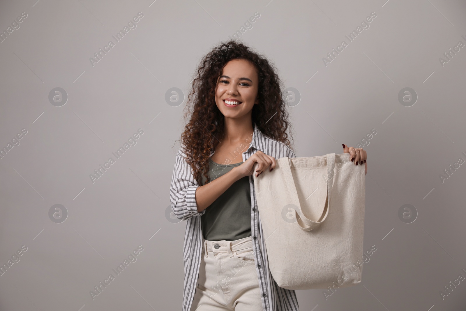 Photo of Happy African-American woman with eco bag on grey background