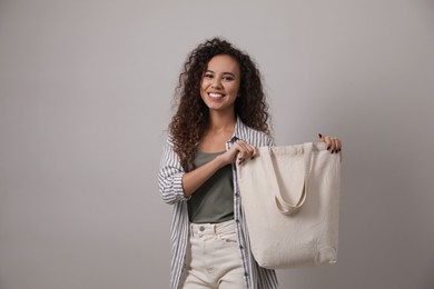 Happy African-American woman with eco bag on grey background