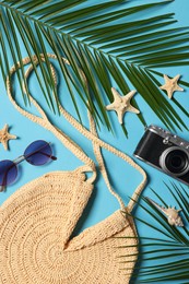 Photo of Flat lay composition with bag, palm leaves and other beach accessories on light blue background