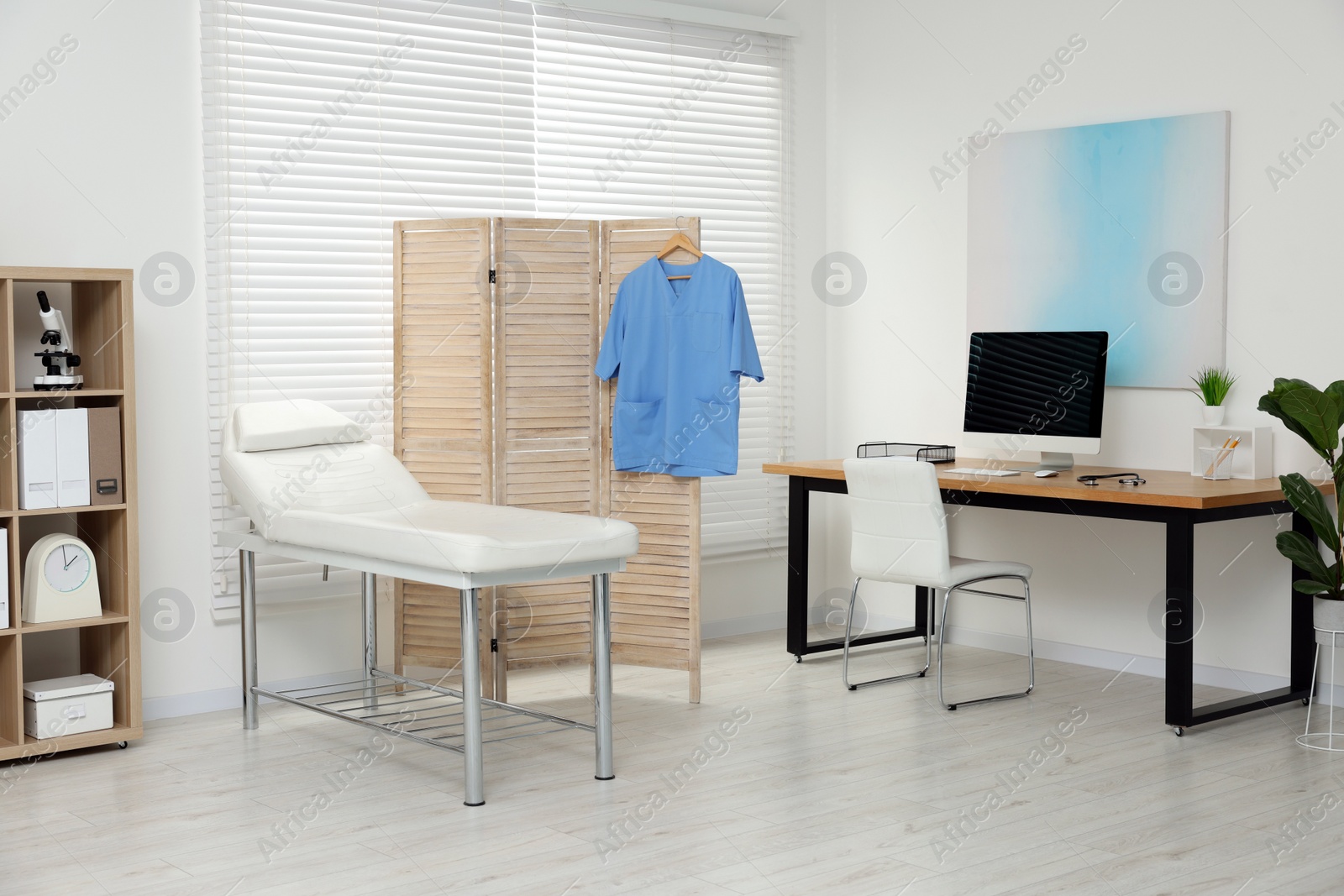 Photo of Modern medical office with doctor's workplace and examination table in clinic