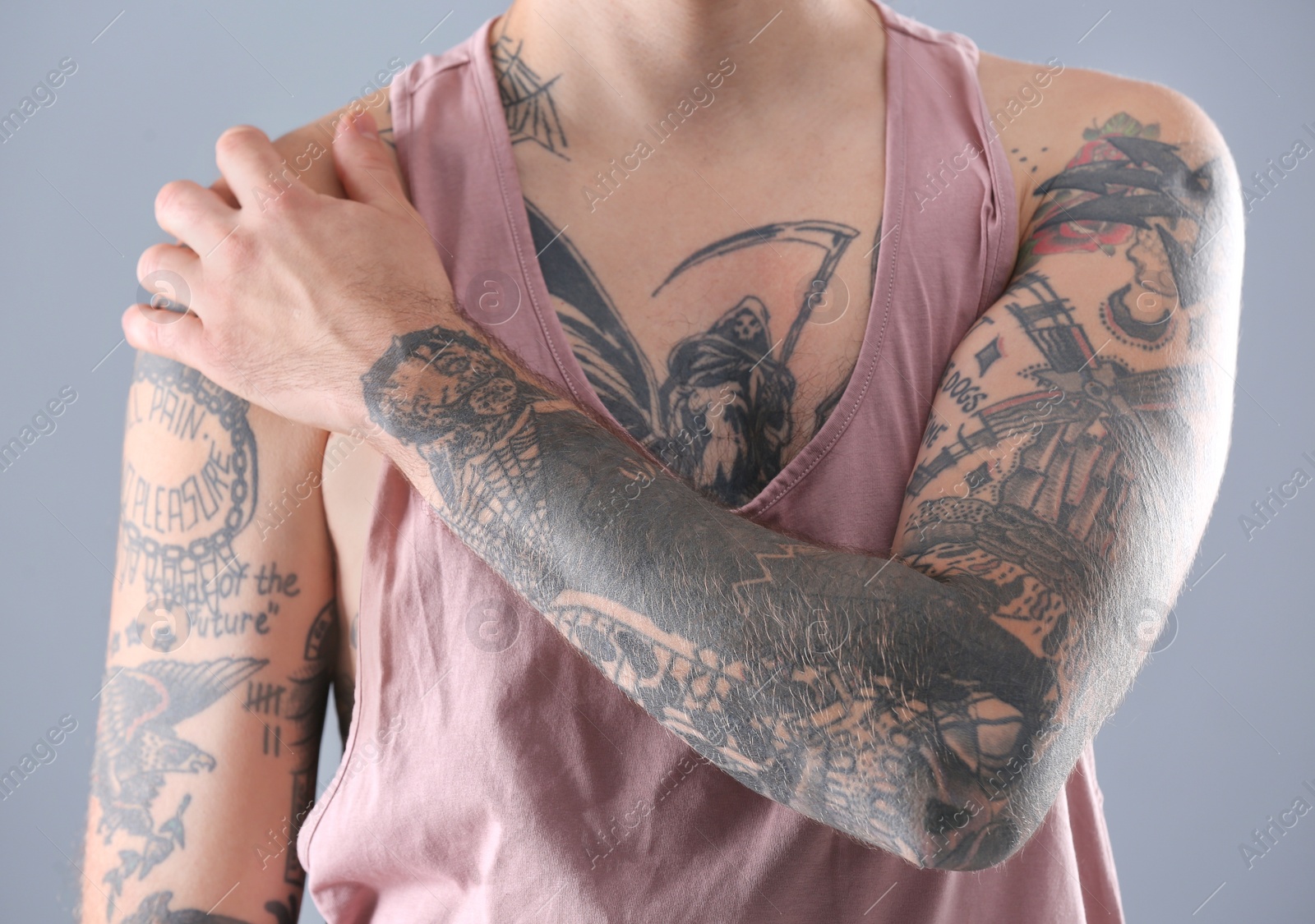 Photo of Young man with stylish tattoos on grey background, closeup