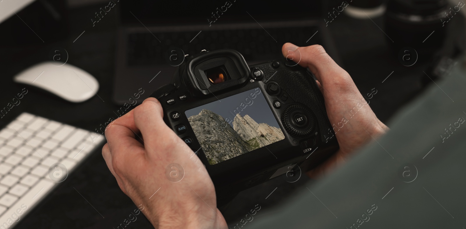 Image of Man with professional photo camera looking at shot of mountain indoors, closeup. Banner design