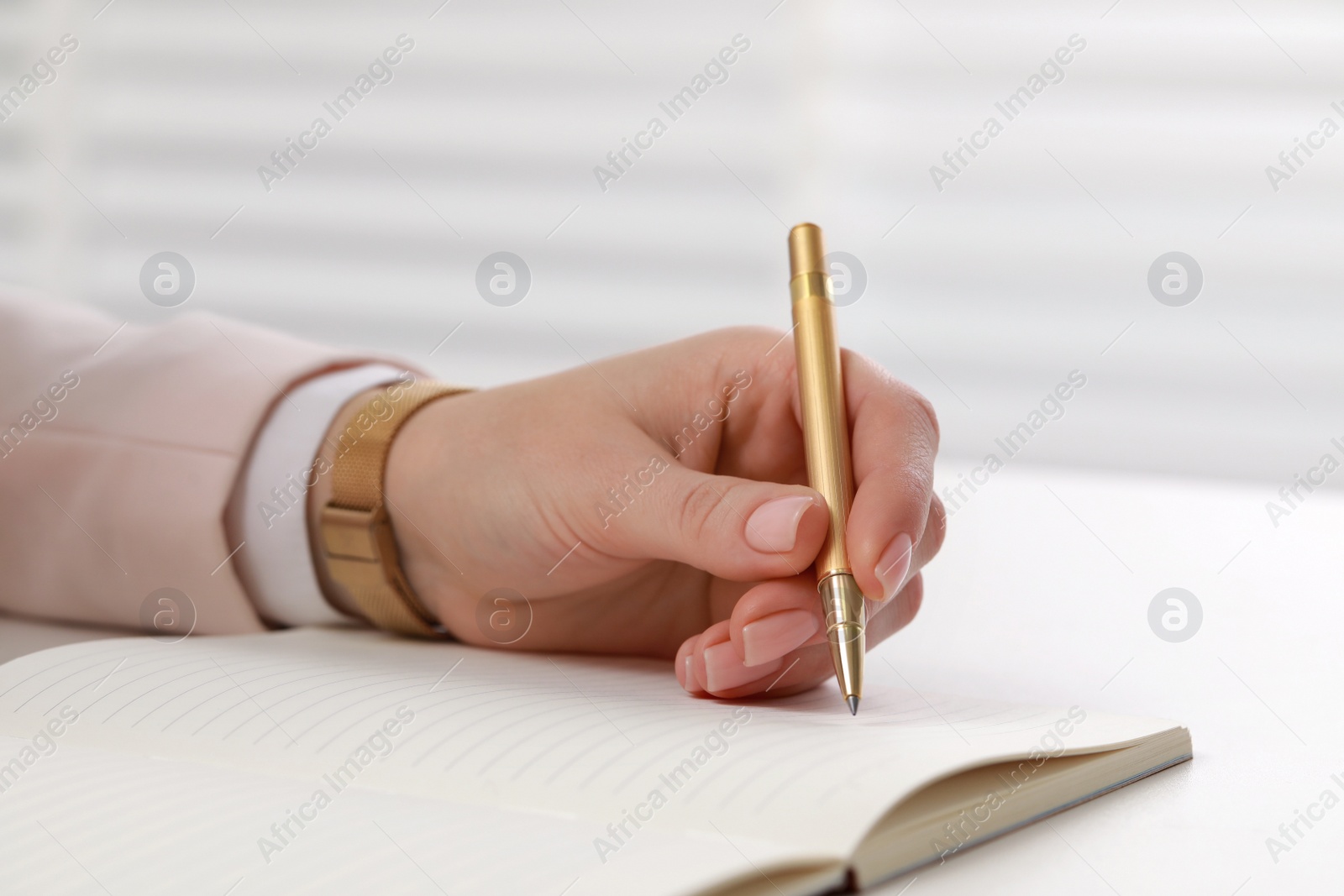 Photo of Woman writing in notebook at white table, closeup