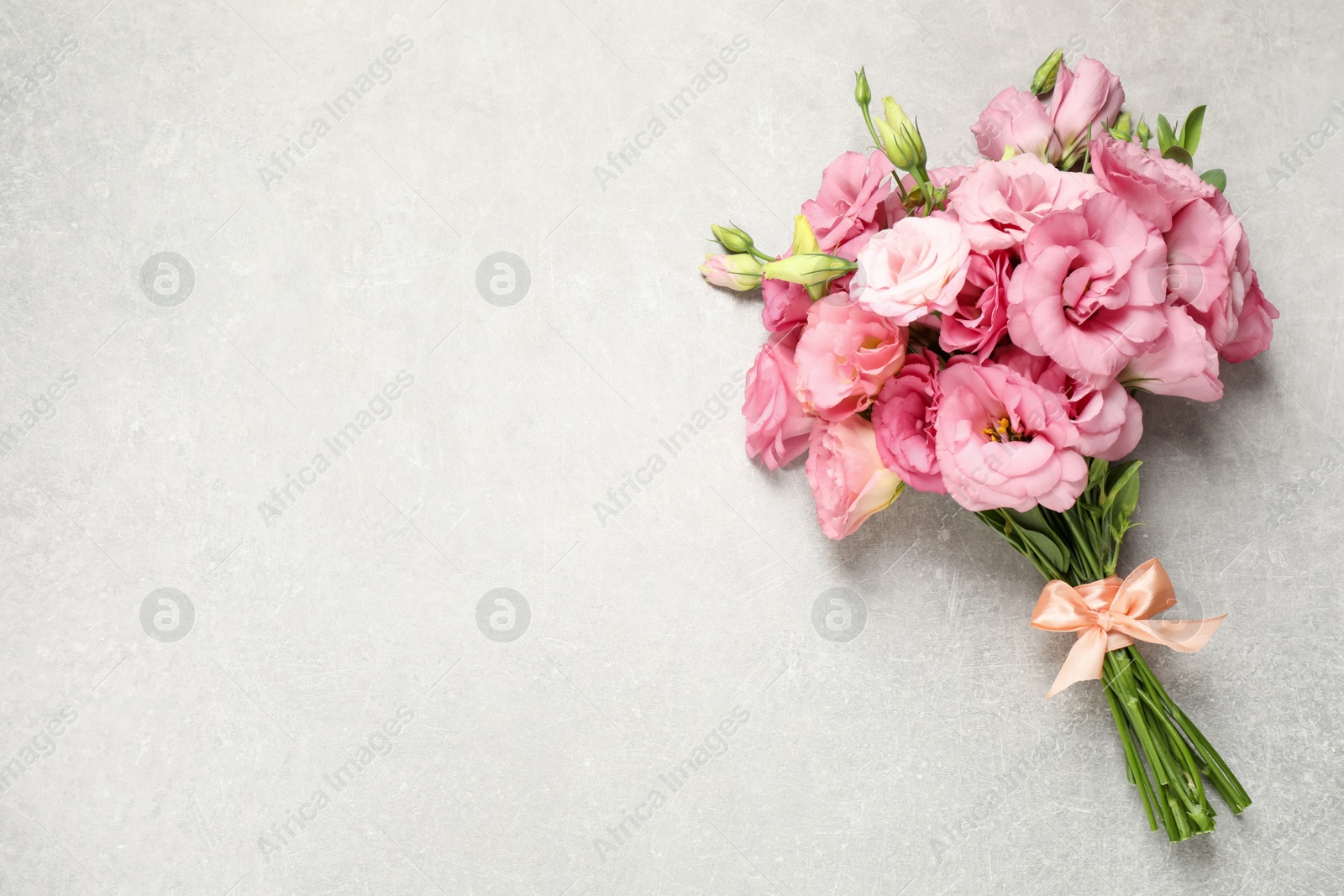 Photo of Beautiful bouquet of pink Eustoma flowers on light grey background, top view. Space for text