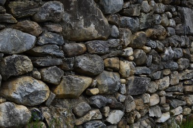 Photo of Wall made of different stones as background, closeup