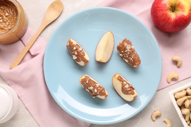 Photo of Slices of fresh apple with nut butter and cashews on table, flat lay